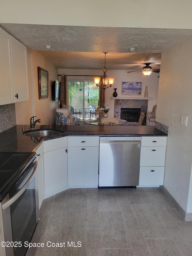 403 Hayes Ave, Cocoa Beach, FL 32931 - kitchen featuring appliances with stainless steel finishes, dark countertops, a fireplace, ceiling fan, and white cabinets