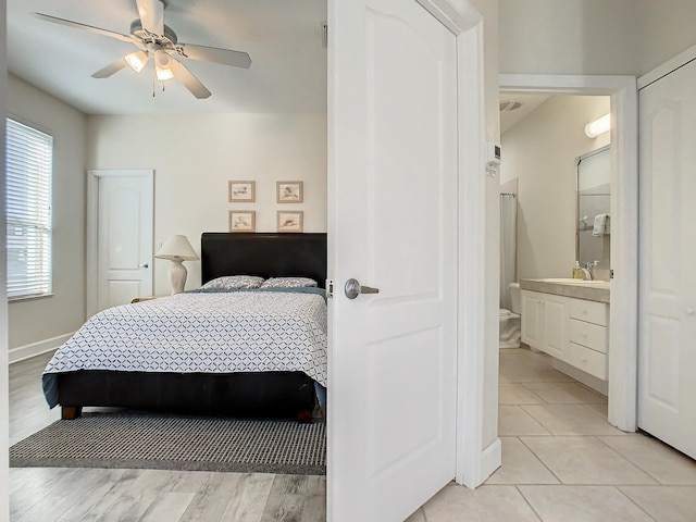 bedroom featuring ensuite bath, sink, light tile patterned floors, and ceiling fan