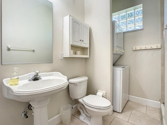 bathroom with toilet, stacked washer and dryer, and tile patterned flooring