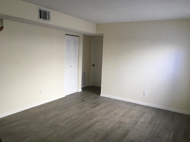 unfurnished room with dark hardwood / wood-style flooring and a textured ceiling