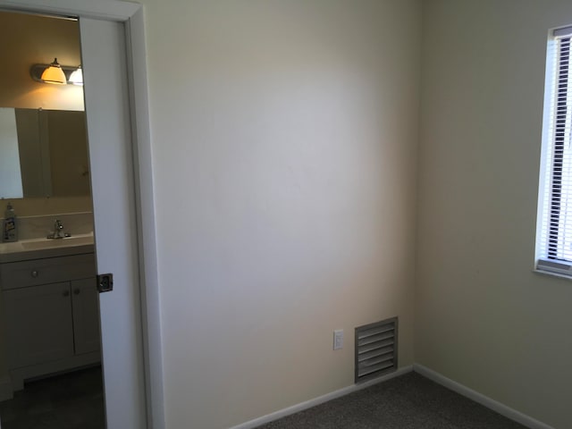 unfurnished room featuring dark carpet and sink