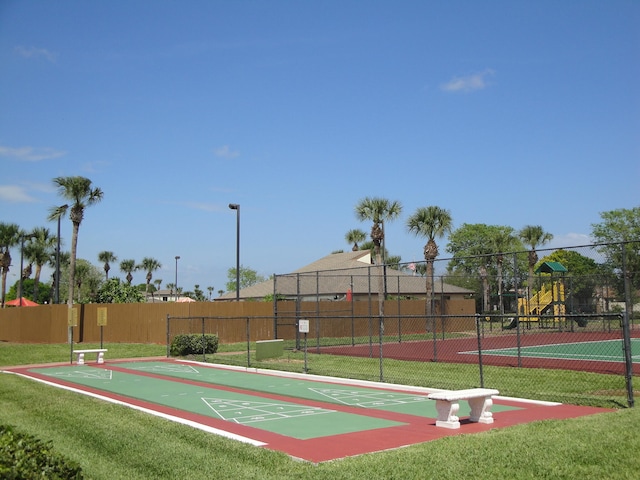 view of sport court featuring a playground and a yard