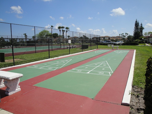 view of nearby features with tennis court and a lawn