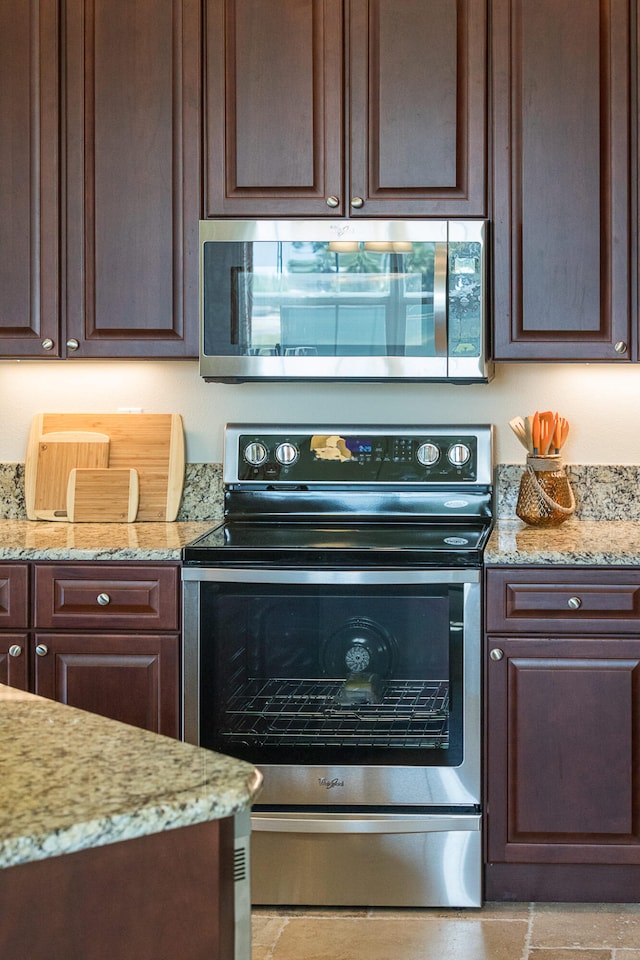 kitchen with appliances with stainless steel finishes, light stone counters, and dark brown cabinetry