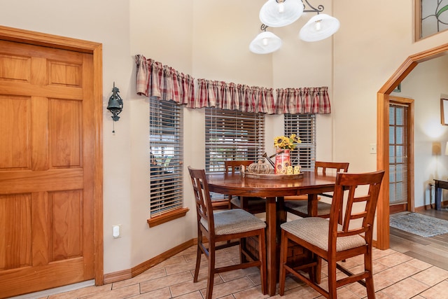 dining room with a high ceiling, a notable chandelier, and light wood-type flooring