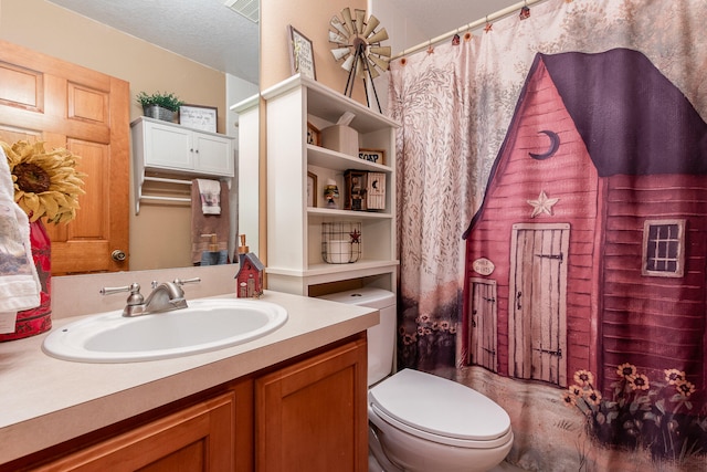 bathroom with toilet, vanity with extensive cabinet space, and a textured ceiling