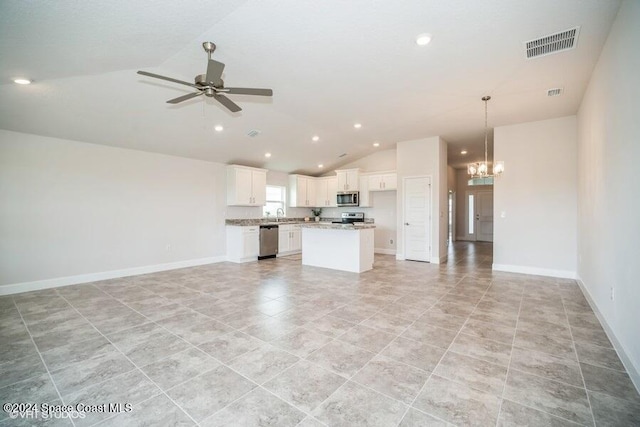 kitchen featuring appliances with stainless steel finishes, hanging light fixtures, a center island, white cabinets, and vaulted ceiling