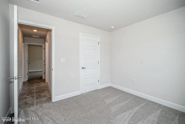 unfurnished bedroom featuring dark colored carpet, a textured ceiling, and a closet