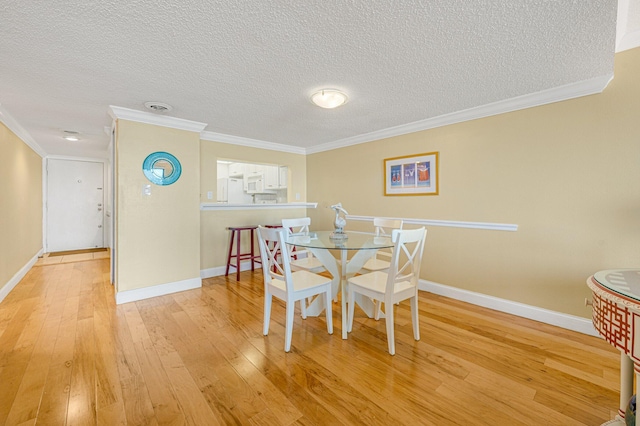 dining room with crown molding, light hardwood / wood-style floors, and a textured ceiling