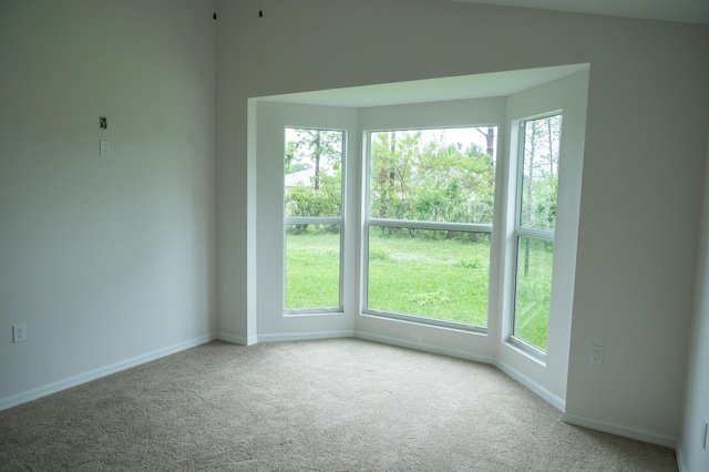 carpeted empty room featuring vaulted ceiling and a wealth of natural light