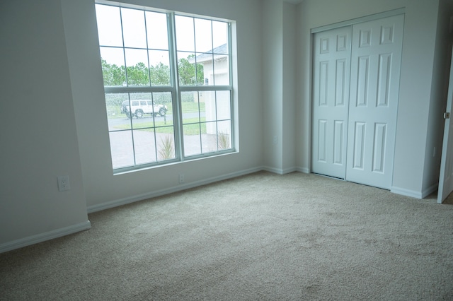 unfurnished bedroom with light colored carpet and a closet