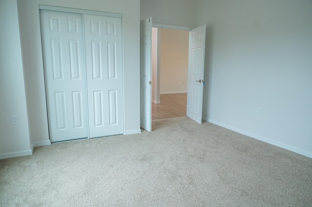 unfurnished bedroom featuring light carpet and a closet