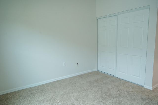 unfurnished bedroom featuring a closet and light colored carpet