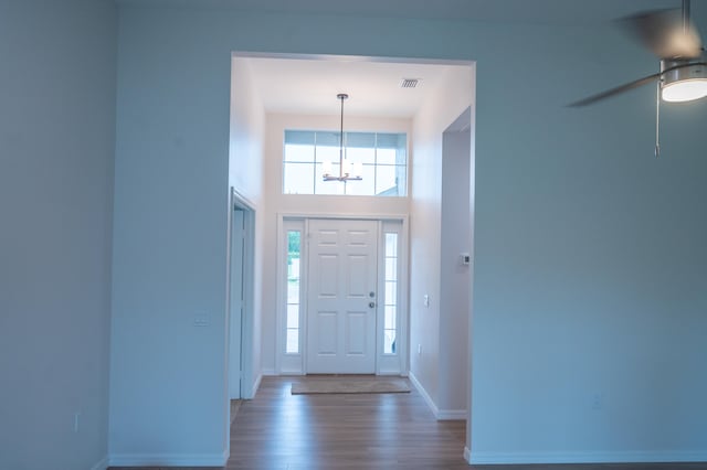 entryway featuring a high ceiling, dark wood-type flooring, and ceiling fan with notable chandelier