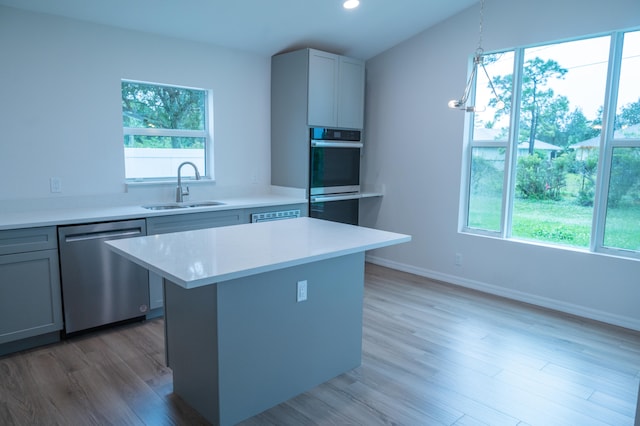 kitchen featuring pendant lighting, sink, gray cabinetry, stainless steel dishwasher, and light wood-type flooring