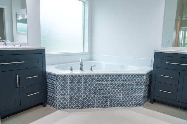 bathroom featuring a relaxing tiled bath, tile flooring, and vanity