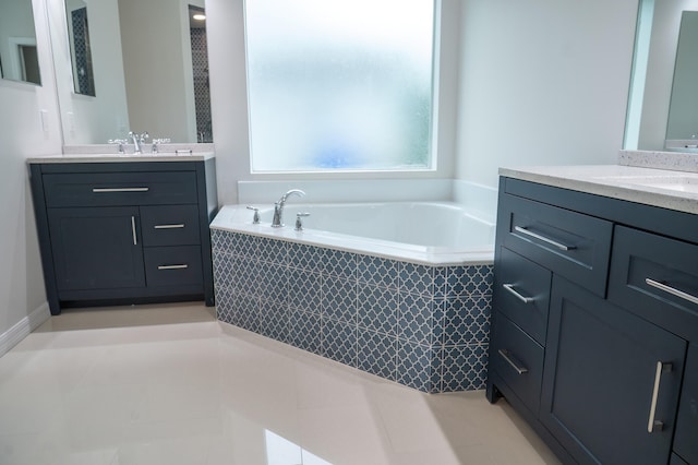 bathroom featuring dual vanity and tiled tub