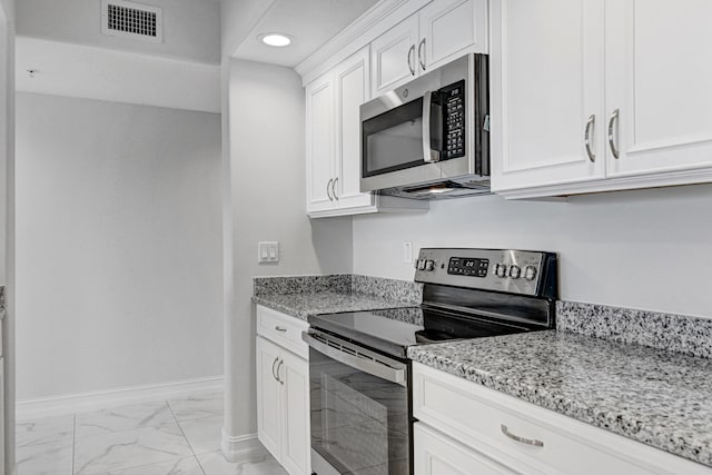 kitchen with white cabinets, light stone countertops, light tile flooring, and stainless steel appliances