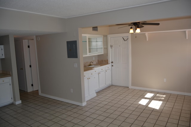 kitchen featuring ceiling fan, light tile flooring, sink, white cabinets, and a textured ceiling