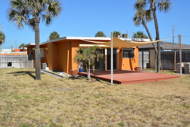 rear view of property featuring a wooden deck, a yard, and central air condition unit