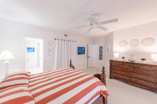 bedroom with ceiling fan, ensuite bathroom, and light colored carpet