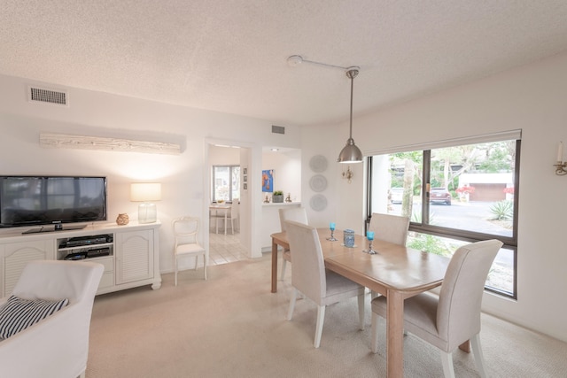 dining space featuring light colored carpet and a textured ceiling