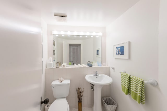 bathroom featuring toilet, tile flooring, and tile walls