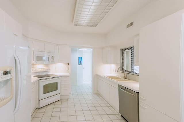 kitchen featuring white cabinets, light tile flooring, white appliances, and sink