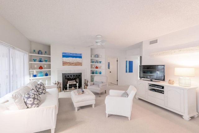 carpeted living room with a textured ceiling, a fireplace, and ceiling fan