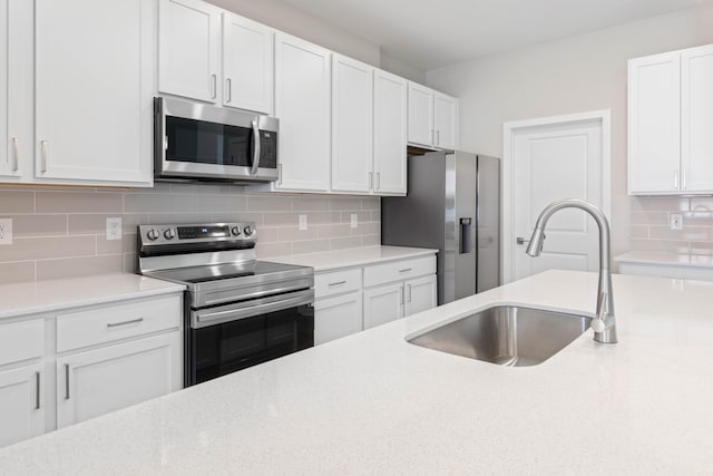 kitchen featuring appliances with stainless steel finishes, backsplash, white cabinetry, and sink