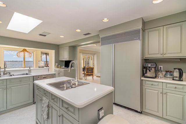 kitchen with a center island with sink, a skylight, sink, and paneled built in fridge