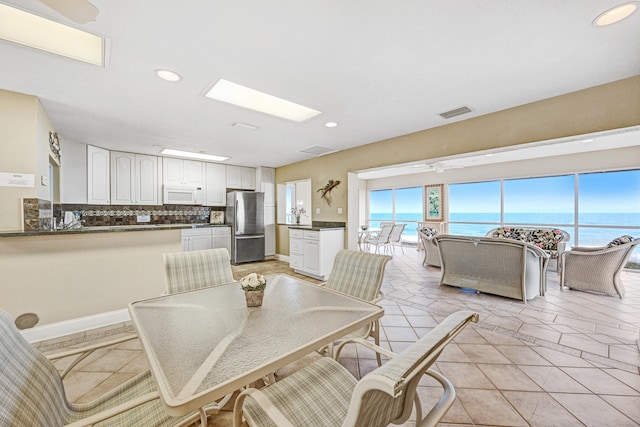 dining area with a water view and ceiling fan