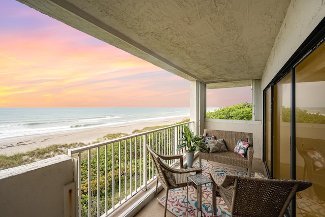 balcony at dusk with a water view and a beach view