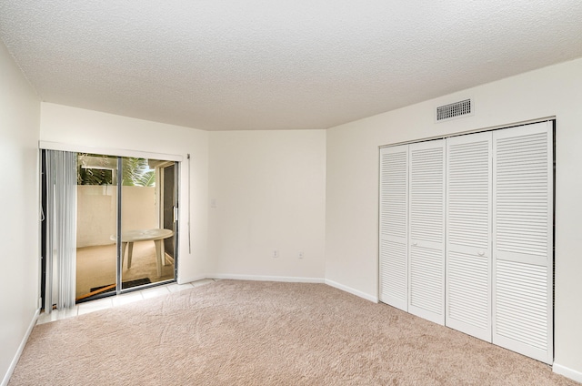 unfurnished bedroom featuring light carpet, a textured ceiling, and a closet