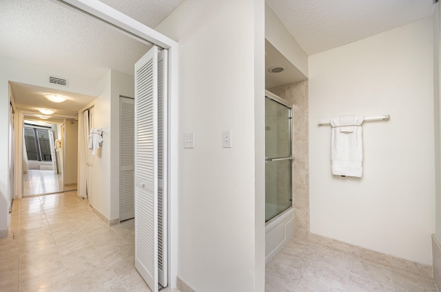 bathroom featuring a textured ceiling, tile patterned flooring, and bath / shower combo with glass door