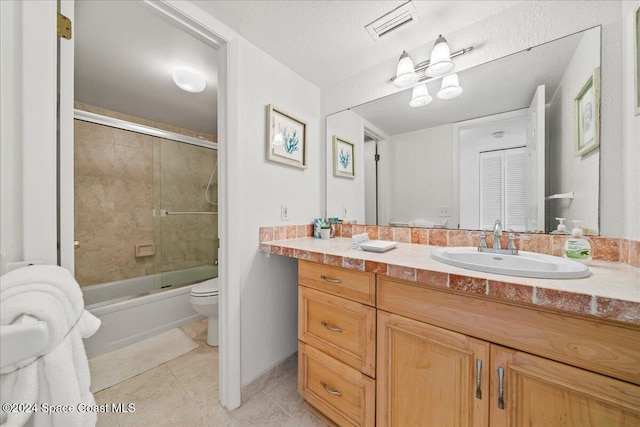 full bathroom with combined bath / shower with glass door, vanity, tile patterned floors, and toilet