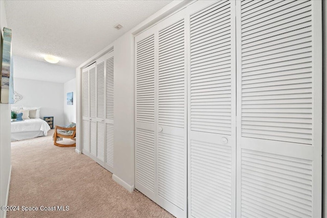 corridor with carpet and a textured ceiling