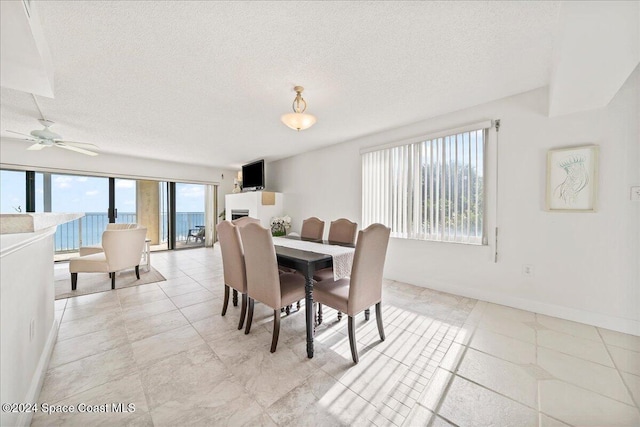 dining space featuring ceiling fan, light tile patterned floors, and a textured ceiling