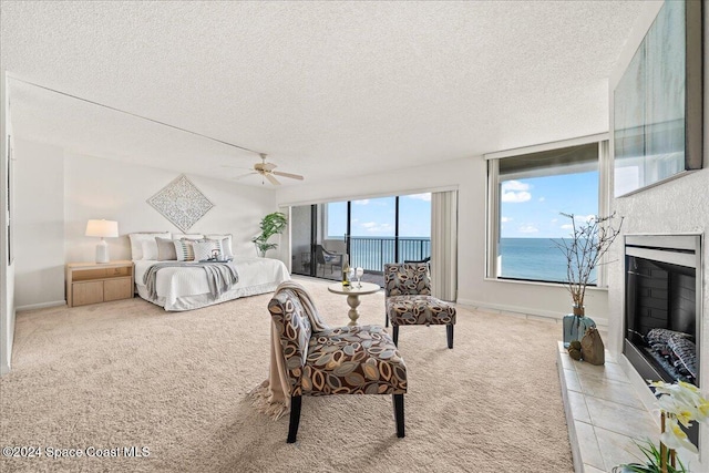 carpeted bedroom featuring ceiling fan, a water view, and a textured ceiling