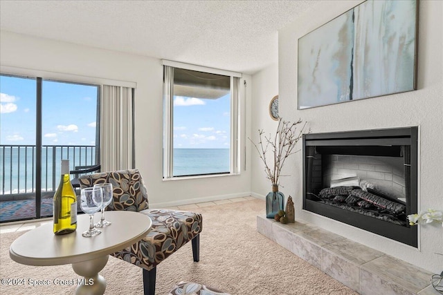 sitting room featuring a tile fireplace, a textured ceiling, and a water view