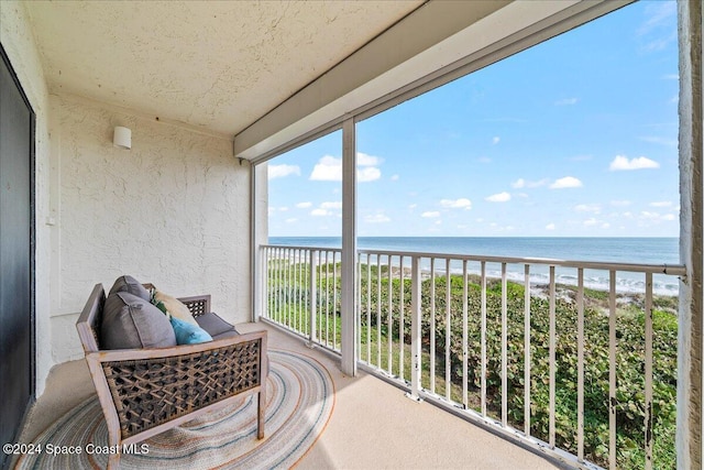 balcony with a water view and a view of the beach