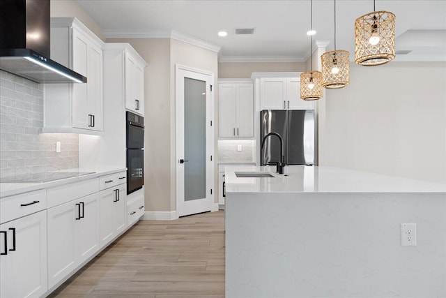 kitchen featuring light hardwood / wood-style floors, wall chimney range hood, backsplash, white cabinetry, and black appliances