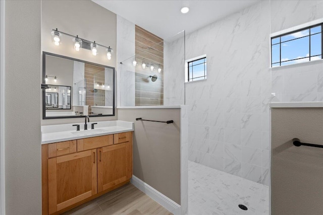 bathroom featuring tiled shower, a healthy amount of sunlight, vanity, and hardwood / wood-style flooring