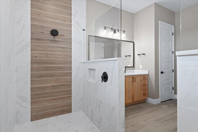 bathroom featuring tiled shower, vanity, and hardwood / wood-style flooring