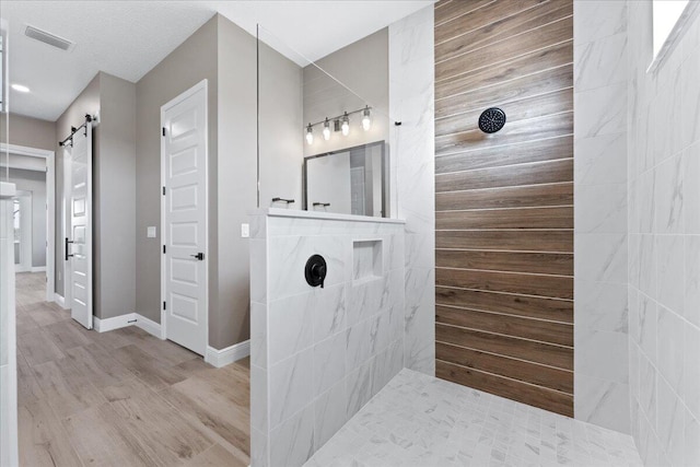 bathroom with hardwood / wood-style floors and a tile shower