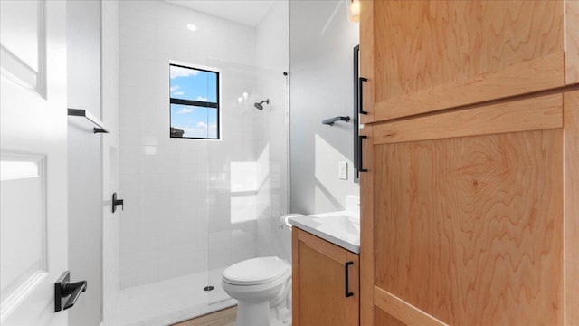 bathroom featuring vanity, toilet, and a tile shower