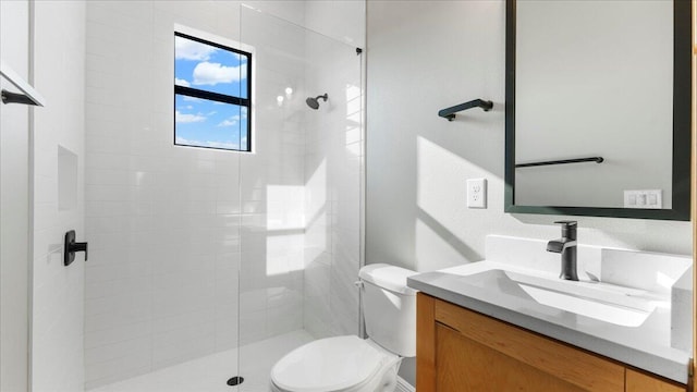 bathroom with vanity, toilet, and tiled shower