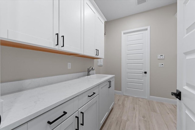 laundry area with sink and light hardwood / wood-style floors