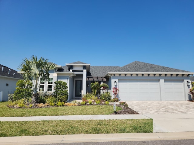 prairie-style house featuring driveway, an attached garage, a front lawn, and stucco siding