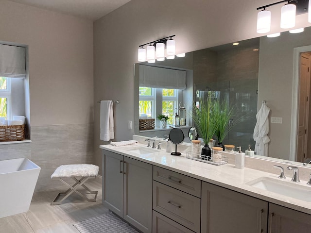 bathroom featuring tile walls, vanity, a bath, and tile patterned flooring